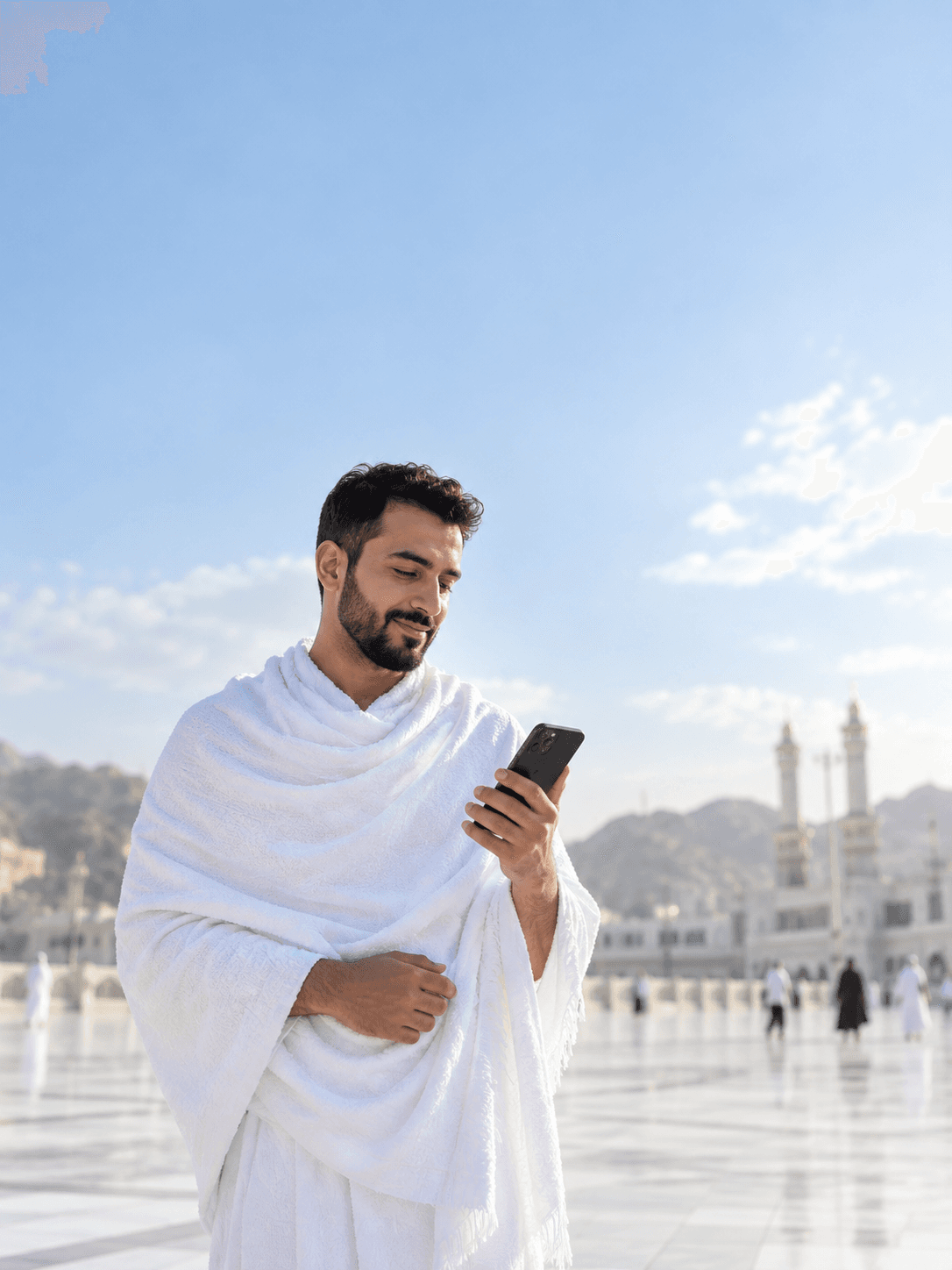 حاج بإحرام ينظر إلى هاتفه بجانب المسجد الحرام