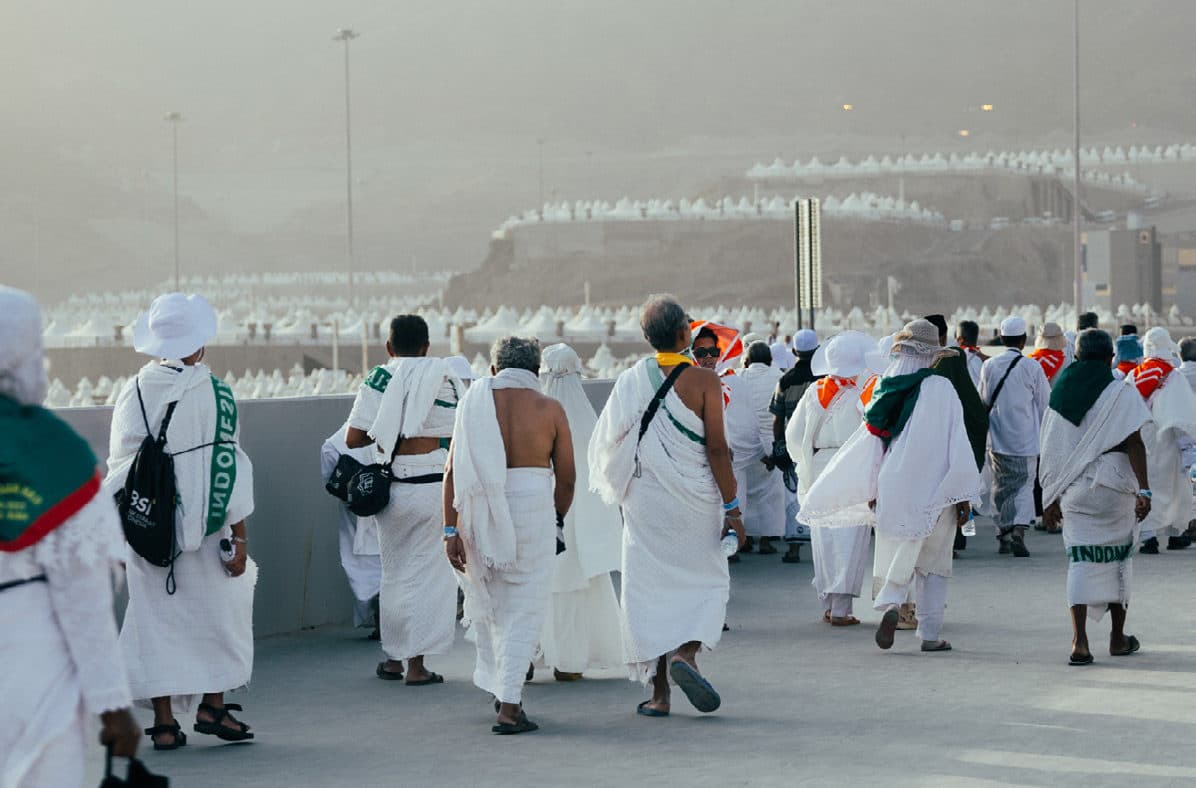 حجاج بلباس الإحرام يسيرون على ممشى باتجاه خيام منى البيضاء