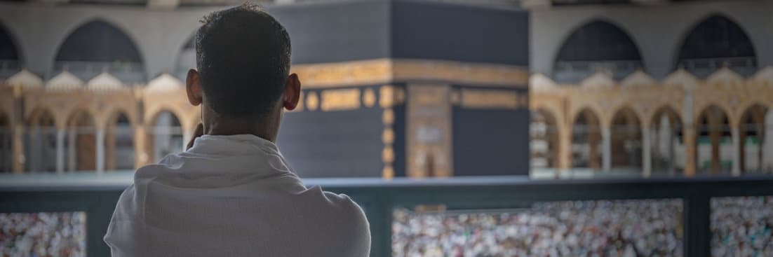 حاج بلباس الإحرام يتأمل الكعبة المشرفة